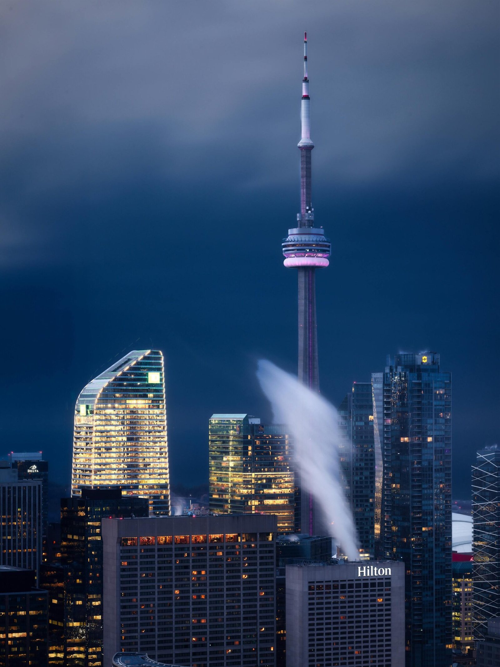 Dramatic night view of Toronto's skyline with the iconic CN Tower and illuminated skyscrapers.